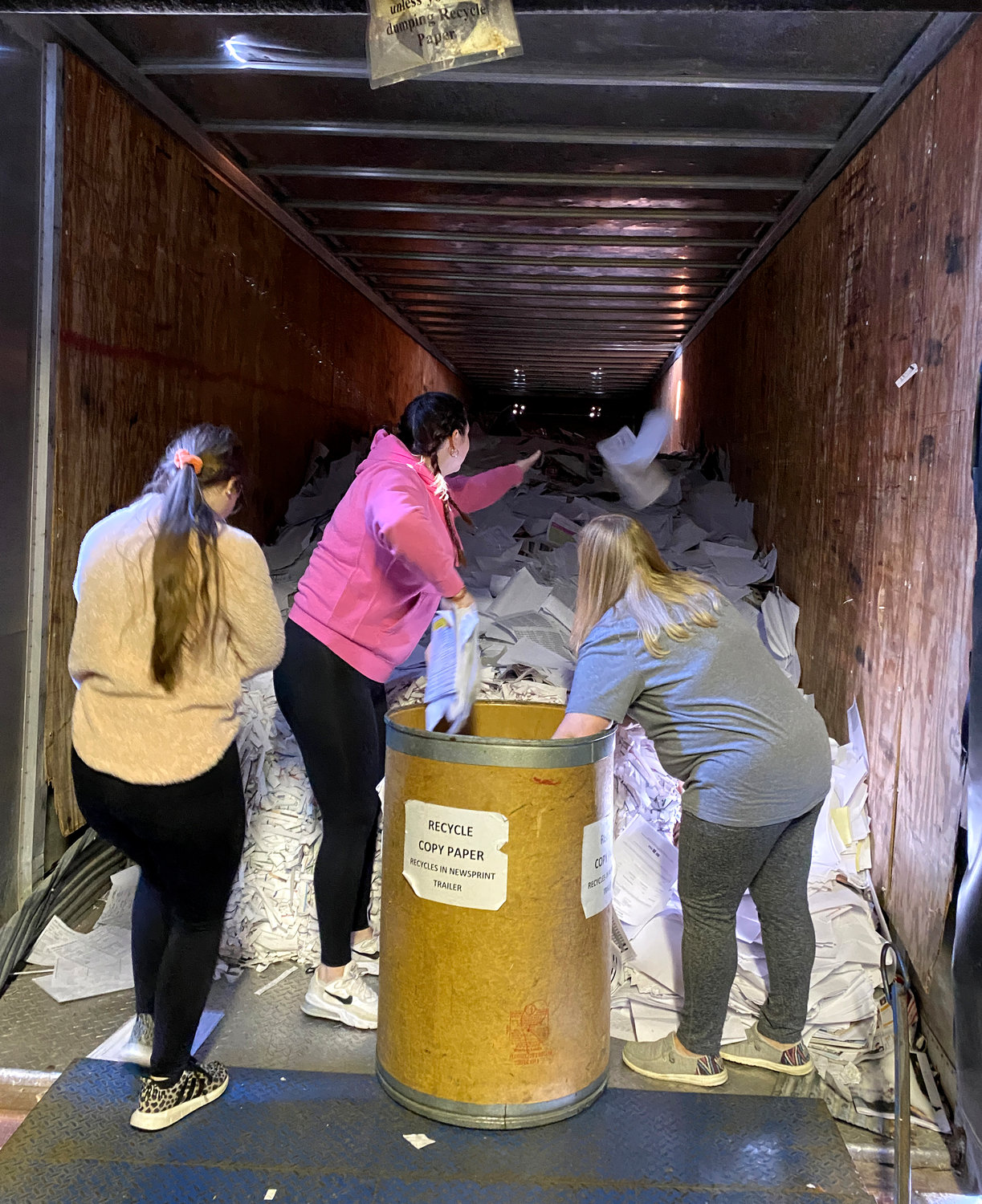 From left, Customer Service Representative Celeste Knox, Advertising Assistant Michele Newton and Customer Service Manager Nikki Monsees throw unneeded documents into the Democrat’s recycling trailer. Previously, it was primarily used for recycling old or discarded newspapers. As of late, it mostly houses old paperwork being cleared out of the office.